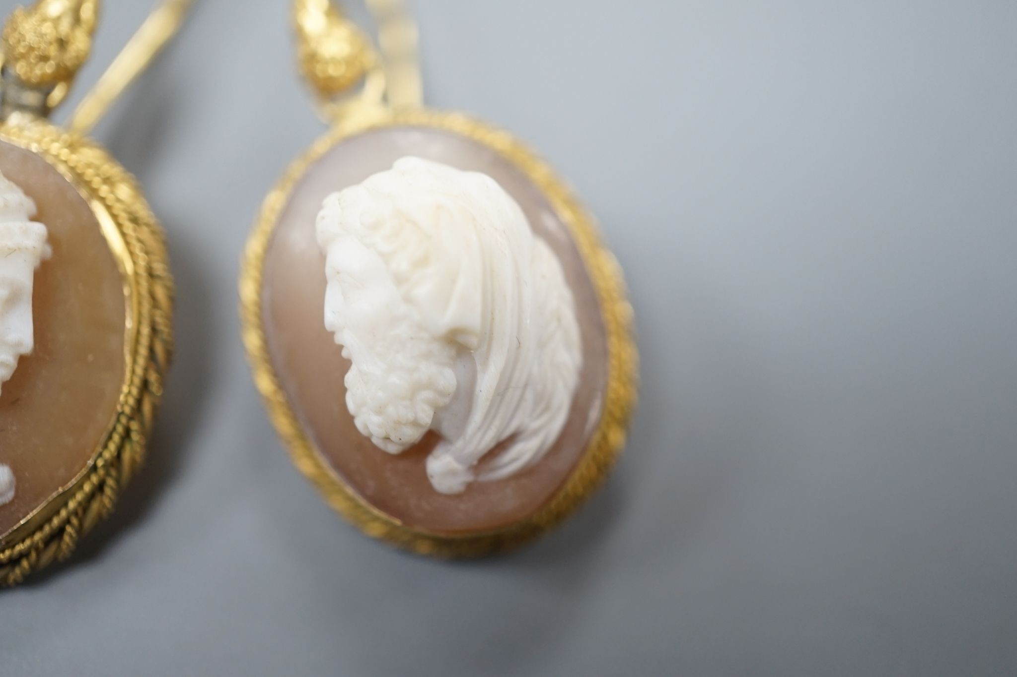 A pair of early 20th century yellow metal and oval cameo shell earrings, carved with a lady to sinister and a gentleman to dexter, overall 40mm, gross 6.2 grams.